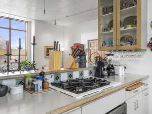 Kitchen with white gas stovetop, white cabinets open great room.