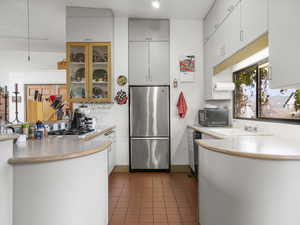 Kitchen with stainless steel appliances, white cabinetry, dark tile patterned floors, and sink