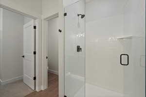 Bathroom with hardwood / wood-style floors, a shower with door, and toilet