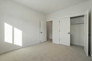 Unfurnished bedroom featuring light carpet and a closet