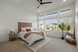 Carpeted bedroom featuring multiple windows and ceiling fan