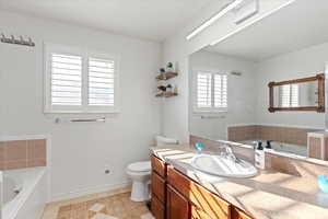 Bathroom featuring tile patterned flooring, vanity, a bathtub, and toilet