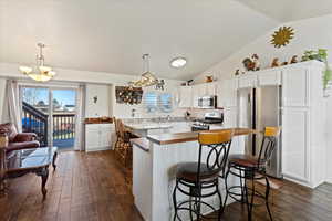 Kitchen featuring plenty of natural light, lofted ceiling, stainless steel appliances, and decorative light fixtures