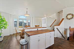 Kitchen with wooden counters, dark hardwood / wood-style flooring, white cabinets, a center island, and hanging light fixtures