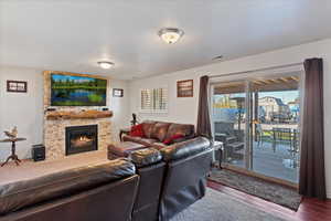 Living room featuring a stone fireplace, wood-type flooring, and a textured ceiling