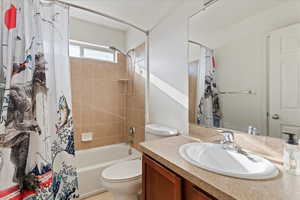 Full bathroom with vanity, shower / bath combo, and toilet