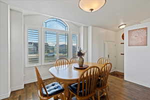 Dining area with dark hardwood / wood-style floors and vaulted ceiling