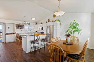 Dining area with lofted ceiling and dark wood- flooring