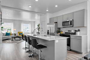 Kitchen with sink, light wood-type flooring, stainless steel appliances, and an island with sink