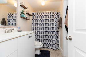 Bathroom with tile patterned flooring, vanity, toilet, and walk in shower