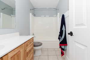 Full bathroom with toilet, vanity, tile patterned floors, and tub / shower combination