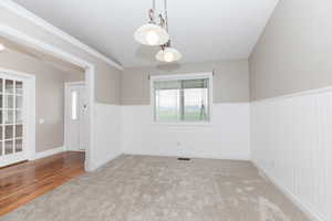 Carpeted spare room featuring crown molding