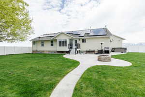 Back of property featuring a lawn, a patio, an outdoor fire pit, and a hot tub