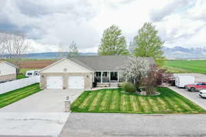 Ranch-style house featuring a mountain view, a garage, and a front lawn