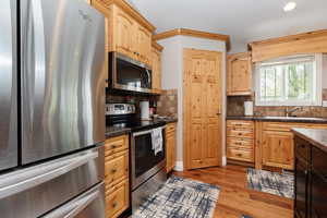 Kitchen featuring decorative backsplash, appliances with stainless steel finishes, sink, light brown cabinets, and light hardwood / wood-style flooring