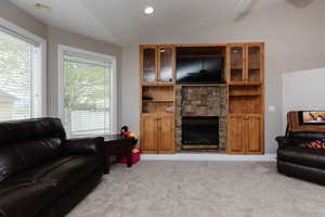 Living room with light colored carpet, lofted ceiling, and a fireplace