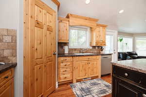 Kitchen with dishwasher, light brown cabinetry, light wood-type flooring, and decorative backsplash