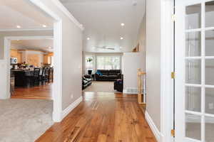 Hallway with light hardwood / wood-style floors and ornamental molding