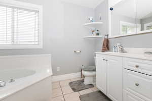 Bathroom with tile patterned floors, vanity, toilet, and a tub