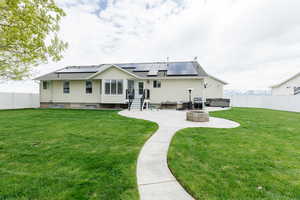 Rear view of house with a patio area, a yard, and a hot tub