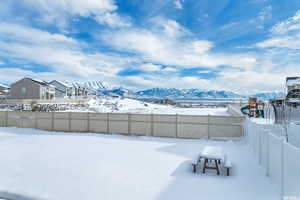 Yard layered in snow featuring a mountain view and a playground