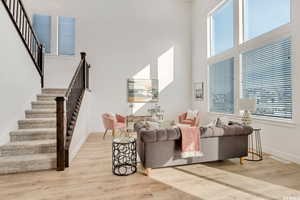 Living room with plenty of natural light, a high ceiling, and light wood-type flooring