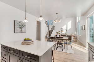 Kitchen with pendant lighting, a center island, light hardwood / wood-style floors, and a notable chandelier