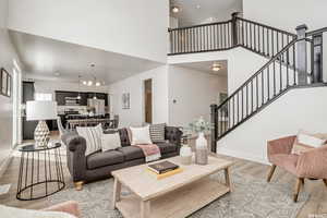 Living room with light hardwood / wood-style floors, a high ceiling, and a chandelier