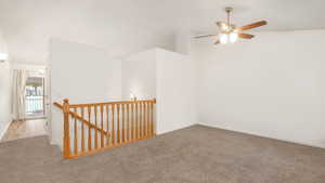 Empty room with ceiling fan, lofted ceiling, and light carpet