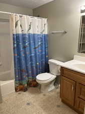 Full bathroom featuring shower / tub combo with curtain, tile patterned flooring, vanity, toilet, and a textured ceiling