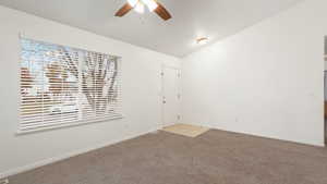 Carpeted empty room with ceiling fan and lofted ceiling