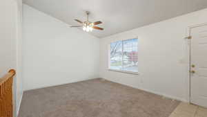 Empty room with ceiling fan, light colored carpet, and vaulted ceiling