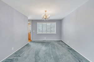 Carpeted spare room with an inviting chandelier