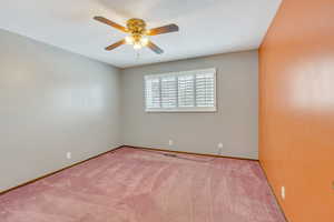 Carpeted spare room featuring ceiling fan