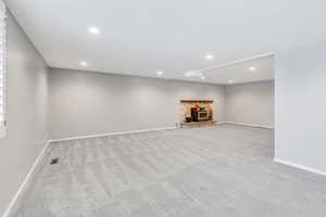 Basement featuring a wood stove and light carpet