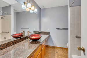 Full bathroom with tile patterned flooring, vanity, tiled shower / bath combo, and toilet