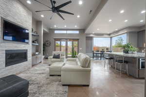 Living room with ceiling fan, a fireplace, and french doors