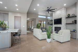 Living room featuring a stone fireplace and ceiling fan