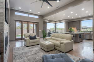 Living room with ceiling fan, a fireplace, and a healthy amount of sunlight