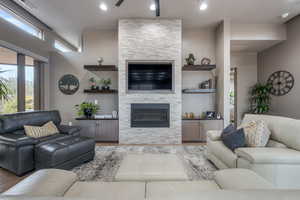 Living room with a fireplace, light hardwood / wood-style flooring, and ceiling fan