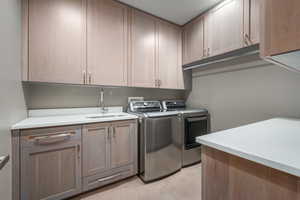 Washroom featuring cabinets, separate washer and dryer, and sink