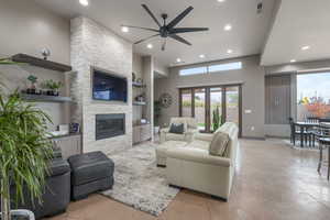 Living room featuring ceiling fan, french doors, built in features, a towering ceiling, and a fireplace