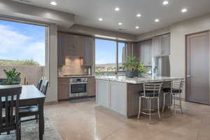 Kitchen with a center island, tasteful backsplash, a kitchen breakfast bar, light stone counters, and appliances with stainless steel finishes