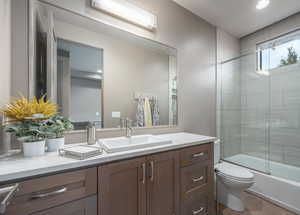 Full bathroom with vanity, enclosed tub / shower combo, and toilet