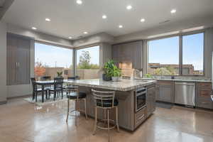 Kitchen with appliances with stainless steel finishes, light stone counters, a breakfast bar, sink, and a kitchen island