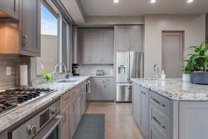 Kitchen with light stone countertops, appliances with stainless steel finishes, and tasteful backsplash