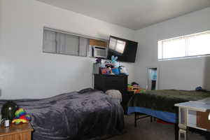 Carpeted bedroom featuring an AC wall unit