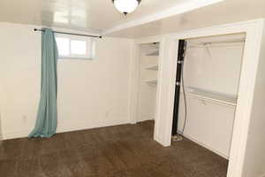 Unfurnished bedroom featuring dark carpet and a closet