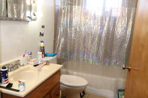 Full bathroom with tile patterned floors, vanity, shower / bath combo, and toilet