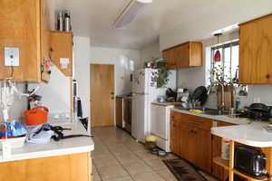 Kitchen featuring white appliances, sink, and light tile patterned floors